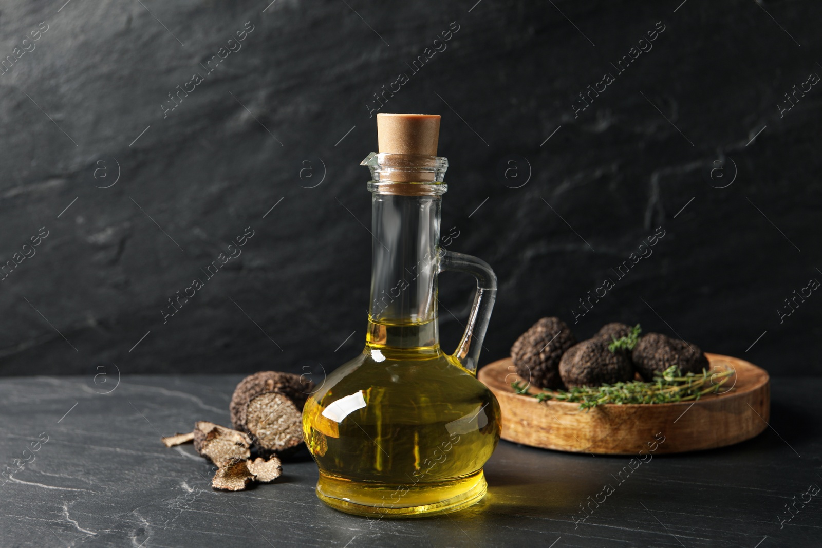 Photo of Fresh truffle oil in glass jug on black table