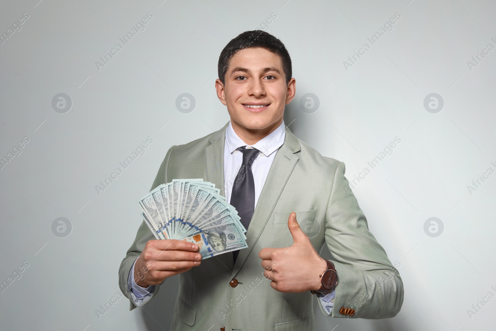 Photo of Portrait of young businessman with money fan on light background