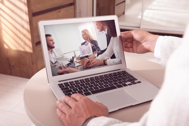 Image of Man attending online video conference via modern laptop at table, closeup