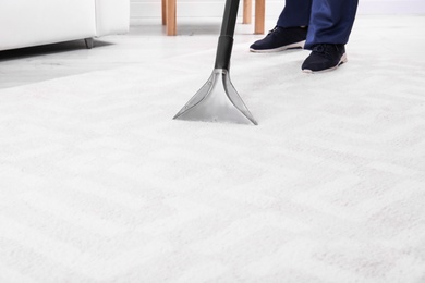 Photo of Man cleaning carpet with vacuum cleaner, closeup. Space for text