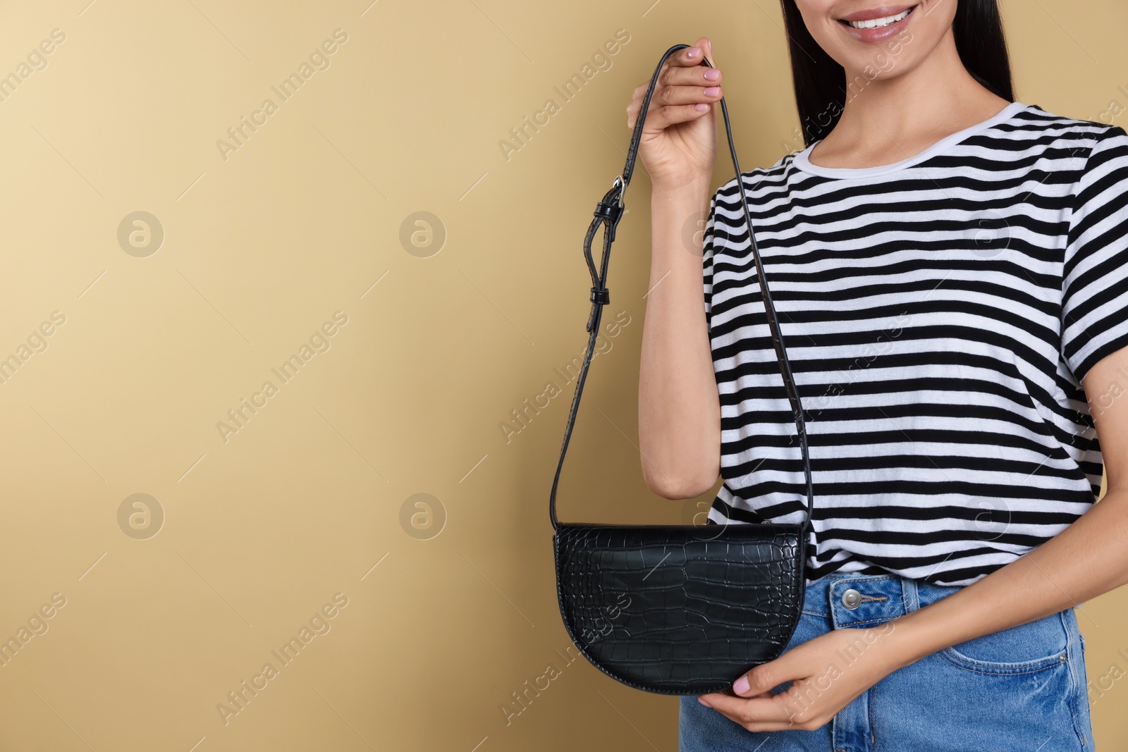 Photo of Woman with stylish bag on beige background, closeup. Space for text