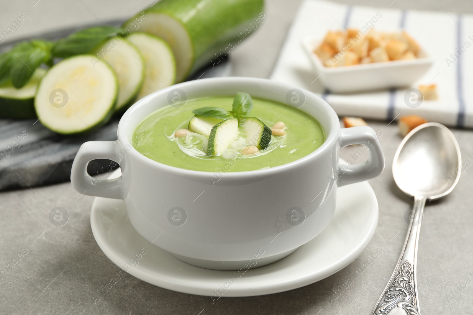 Photo of Tasty homemade zucchini cream soup served on grey table