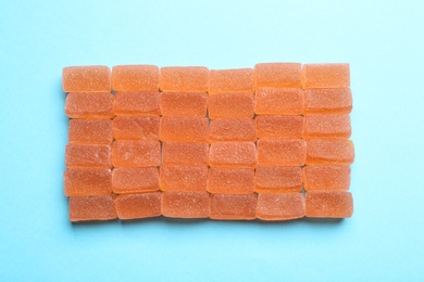 Photo of Tasty orange jelly candies on turquoise background, flat lay