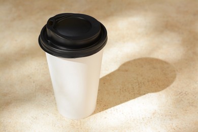 Takeaway coffee cup on beige table, space for text