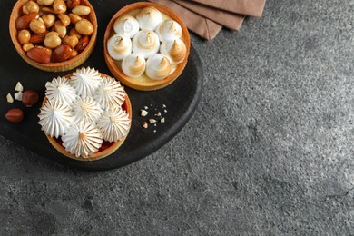 Photo of Different tartlets on dark grey table, flat lay with space for text. Tasty dessert