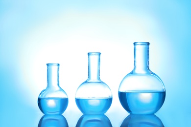 Photo of Laboratory glassware with liquid on color background. Solution chemistry