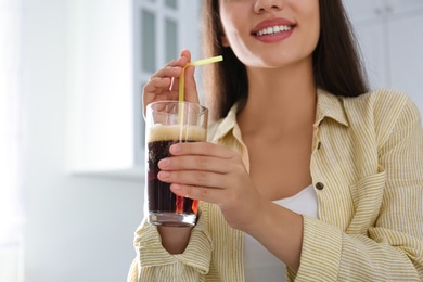 Young woman with cold kvass indoors, closeup. Traditional Russian summer drink