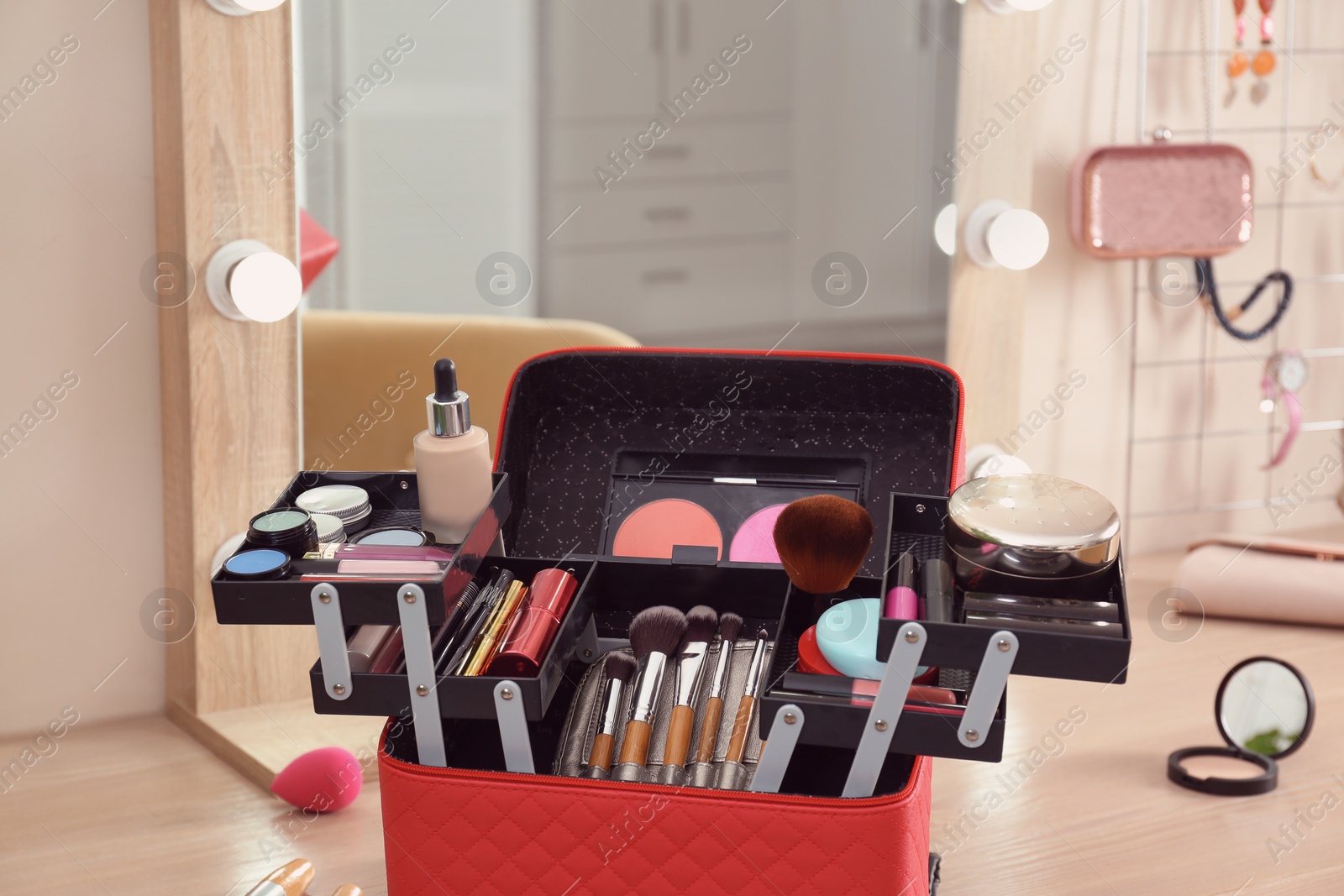 Photo of Beautician case with professional makeup products and tools on wooden dressing table