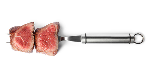 Photo of Carving fork with slices of delicious beef tenderloin isolated on white, top view
