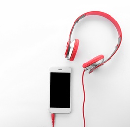 Photo of Smartphone with blank screen and headphones on white background, top view