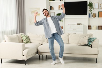 Emotional man dancing while listening music with headphones at home