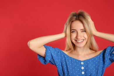 Photo of Portrait of beautiful young woman with blonde hair on red background