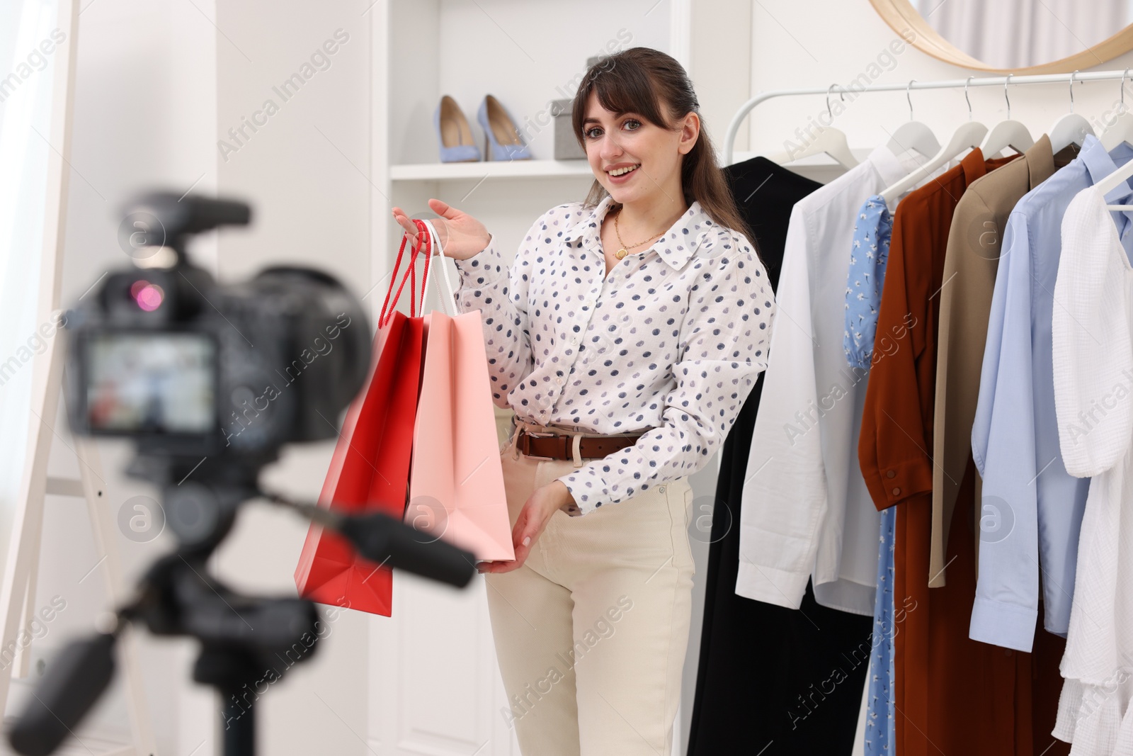 Photo of Smiling fashion blogger with shopping bags recording video at home