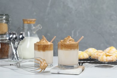 Photo of Glasses of delicious dalgona coffee and whisk on white table