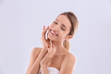 Young woman with silky skin on light background