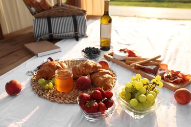 Romantic date. Delicious snacks for picnic on white blanket outdoors