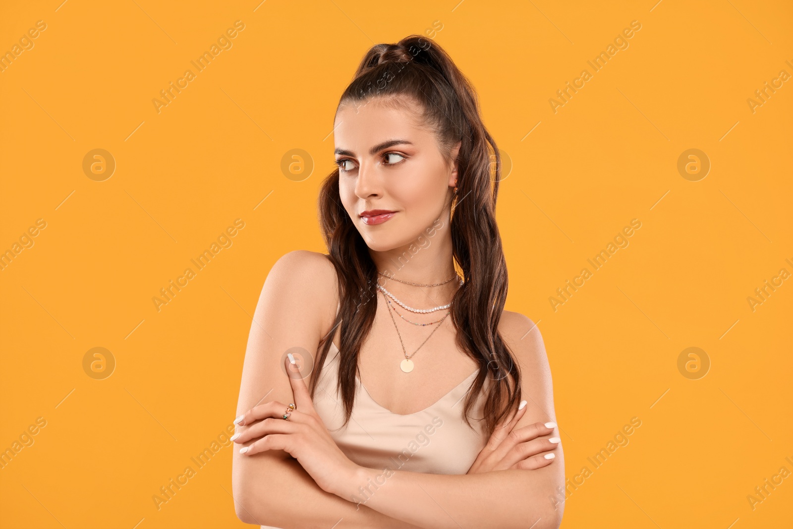 Photo of Beautiful woman with elegant jewelry on orange background