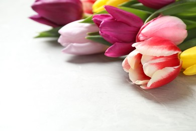 Photo of Beautiful spring tulips on marble table, closeup. Space for text