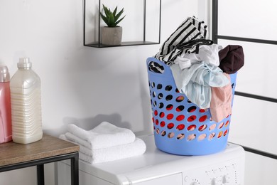 Laundry basket overfilled with clothes on washing machine in bathroom