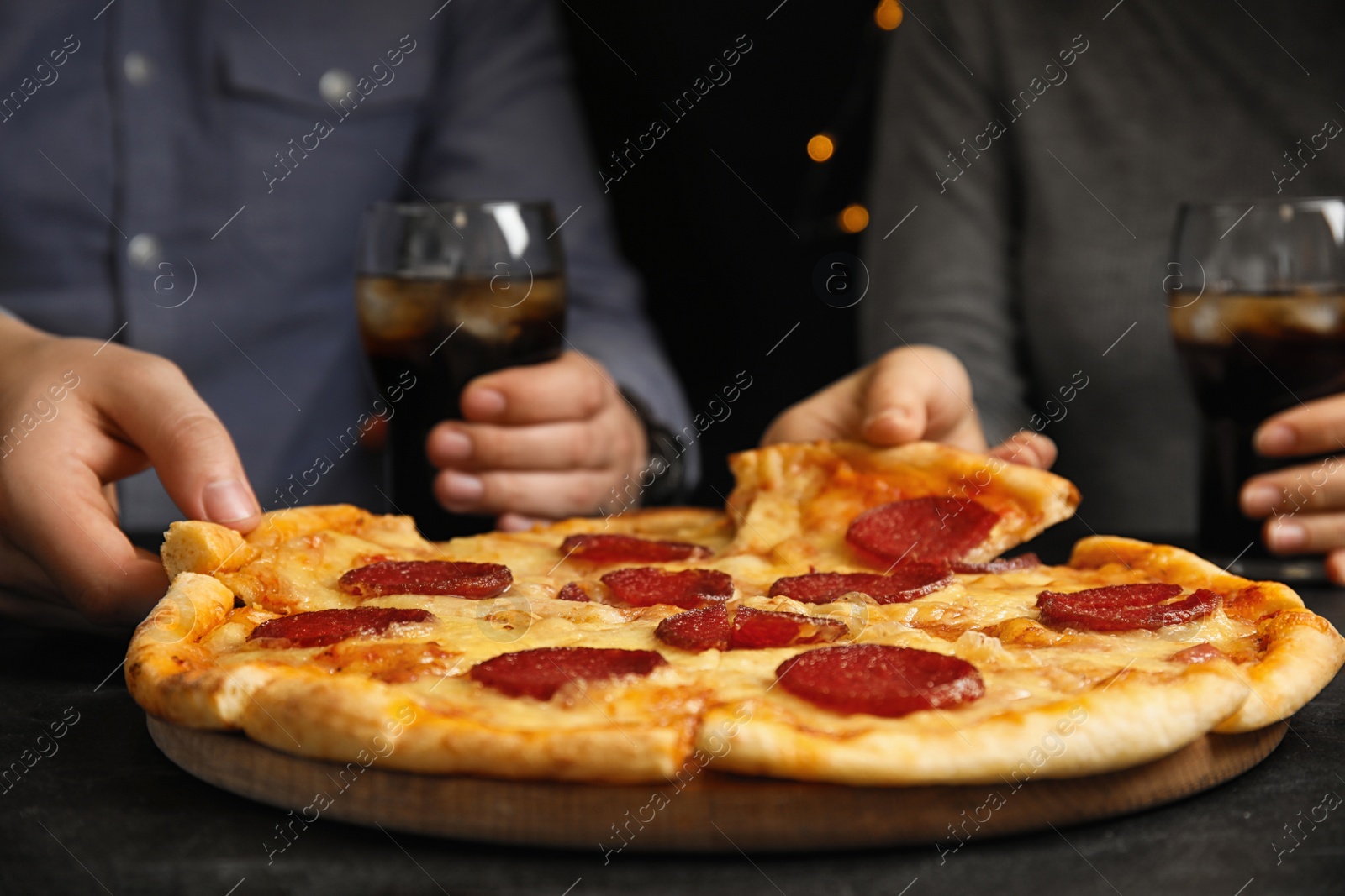 Photo of Friends taking tasty pepperoni pizza at table, closeup