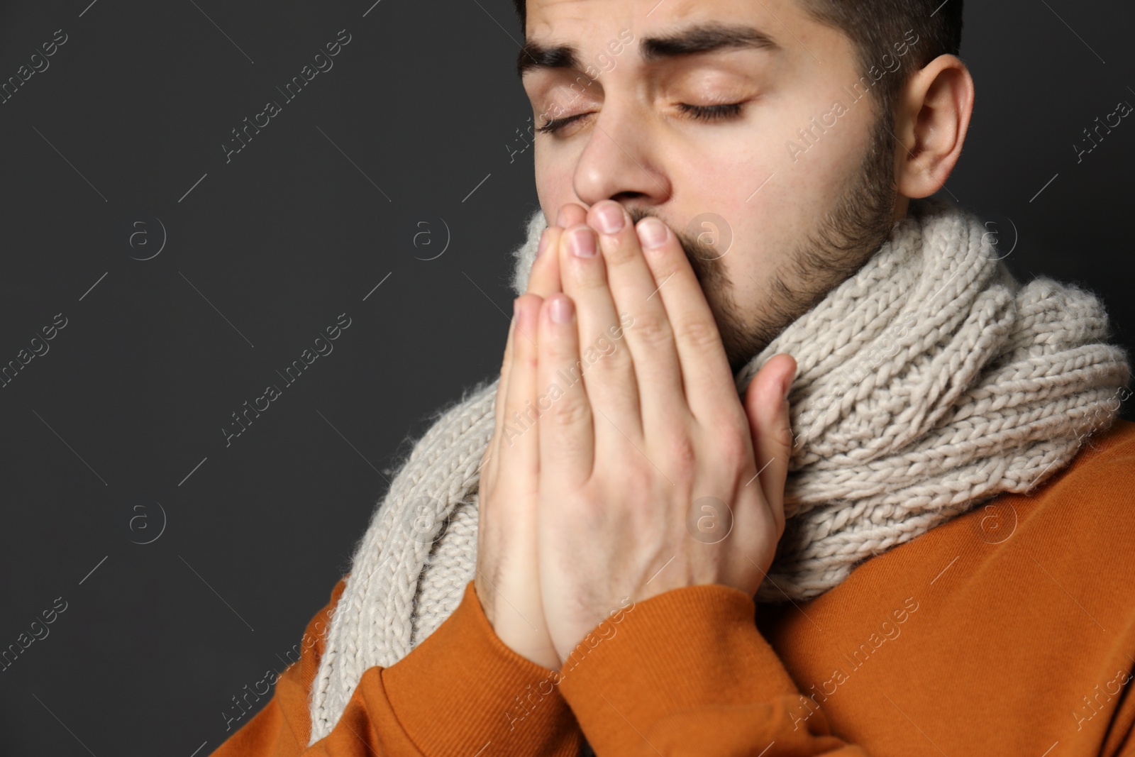 Photo of Handsome young man coughing against dark background. Space for text