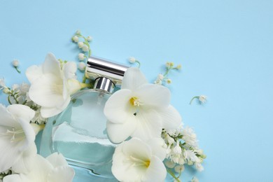 Photo of Luxury perfume and floral decor on light blue background, above view. Space for text