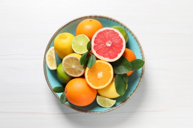 Photo of Different cut and whole citrus fruits on white wooden table, top view