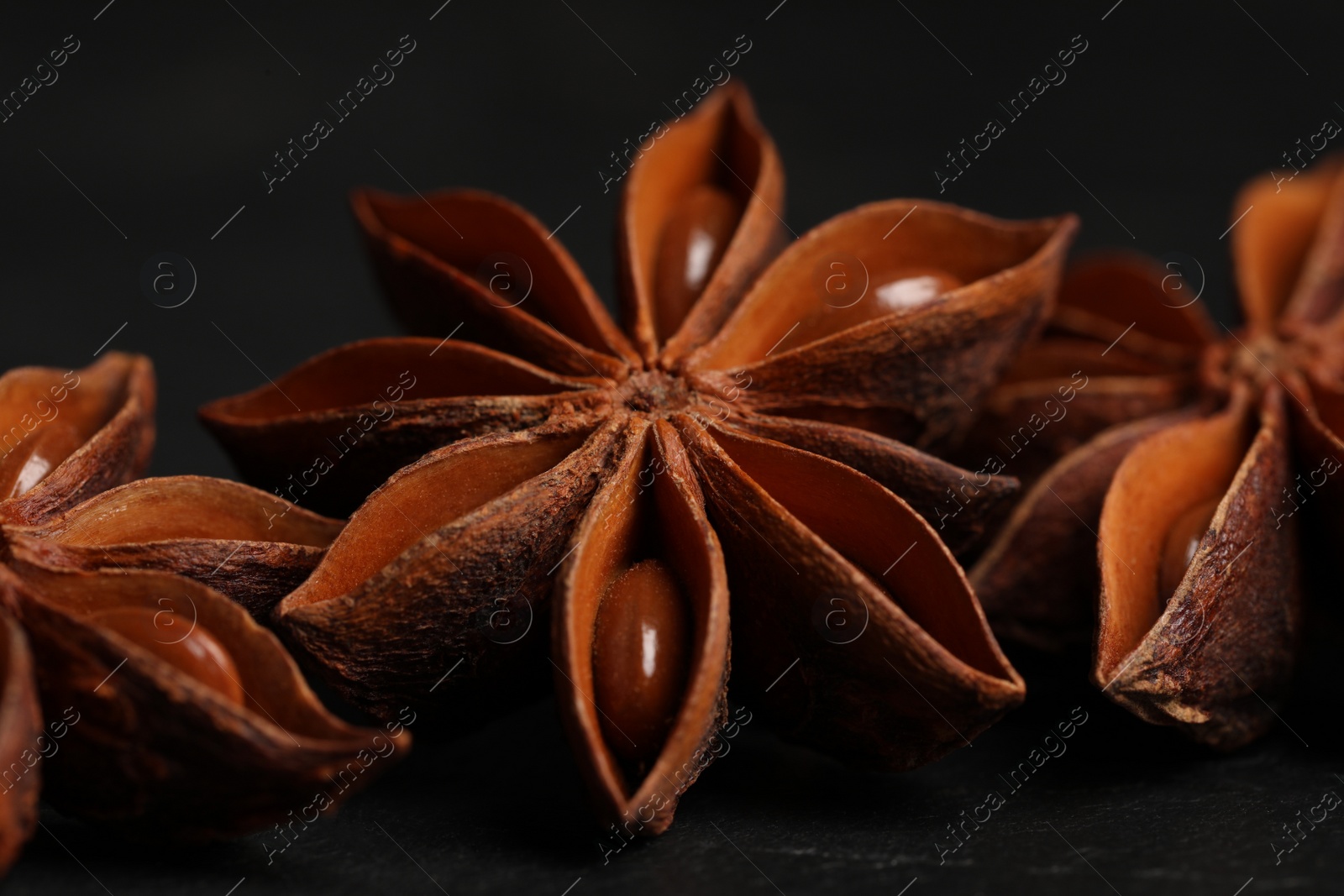 Photo of Aromatic anise stars on black table, closeup