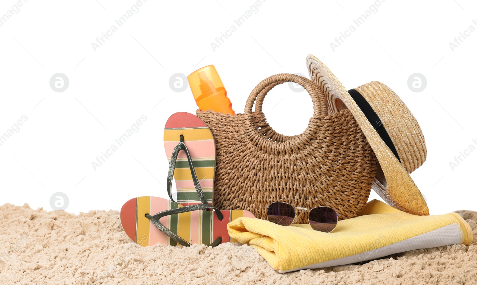 Photo of Stylish bag with beach accessories on sand against white background