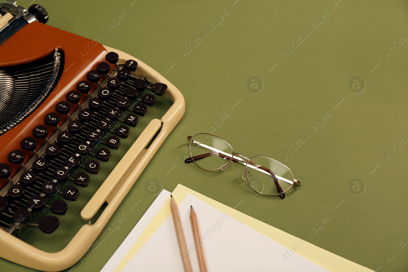 Photo of Vintage typewriter, glasses and stationery on dark green background, space for text