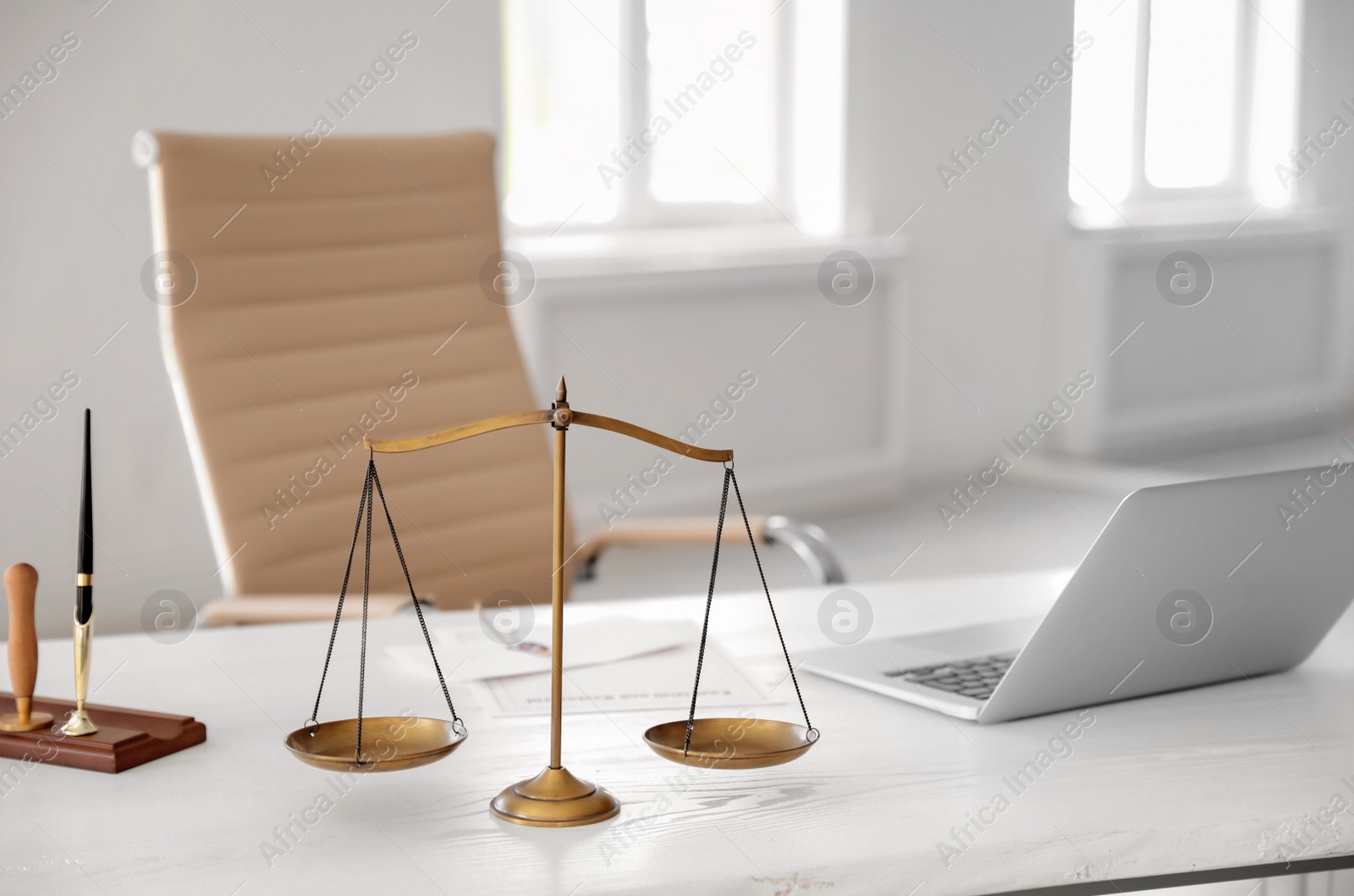 Photo of Scales of justice and laptop on desk in notary's office