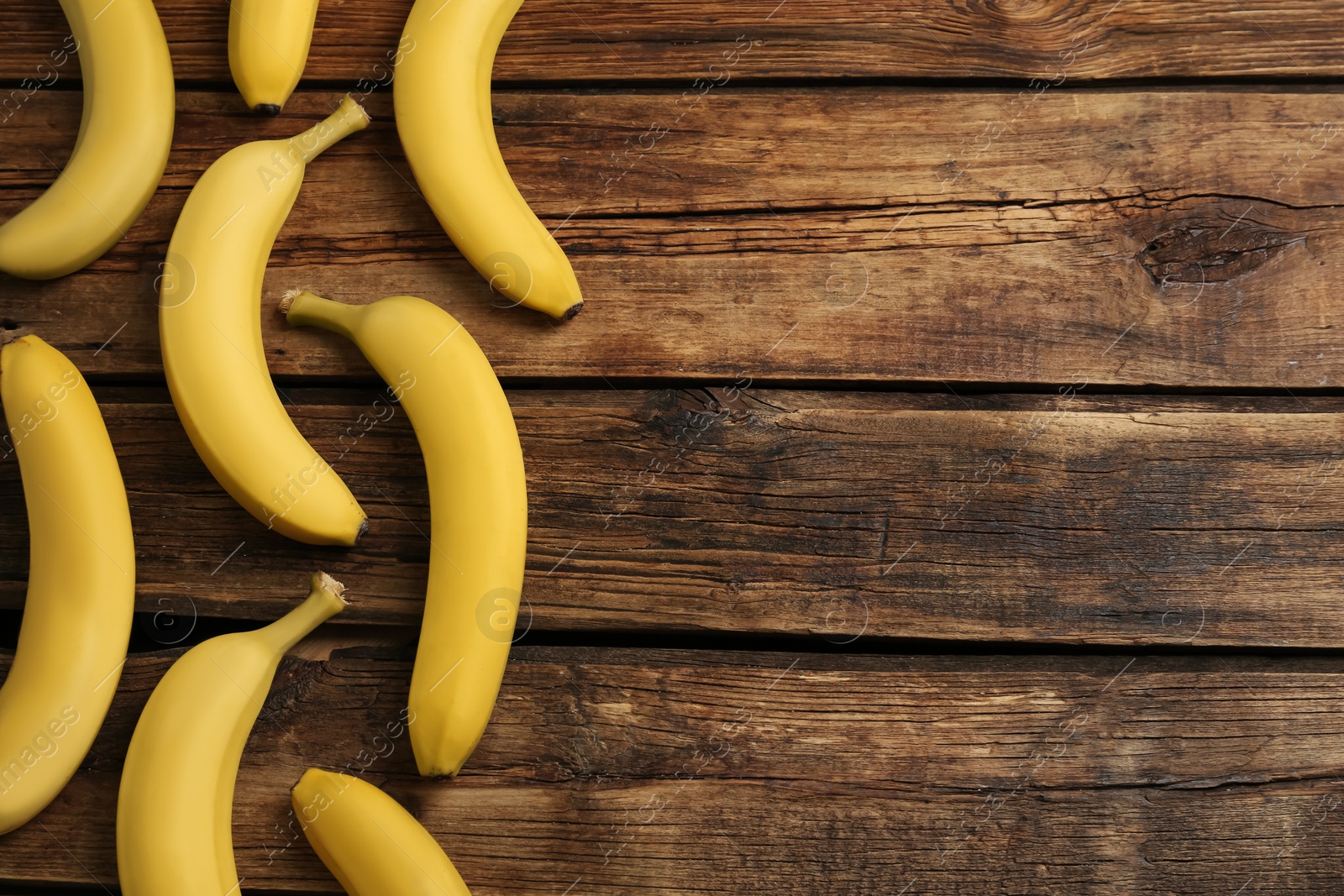 Photo of Ripe sweet yellow bananas on wooden table, flat lay. Space for text