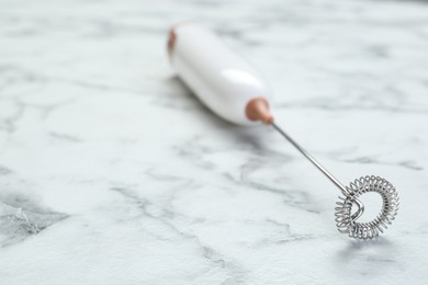 Milk frother wand on white marble table, closeup. Space for text