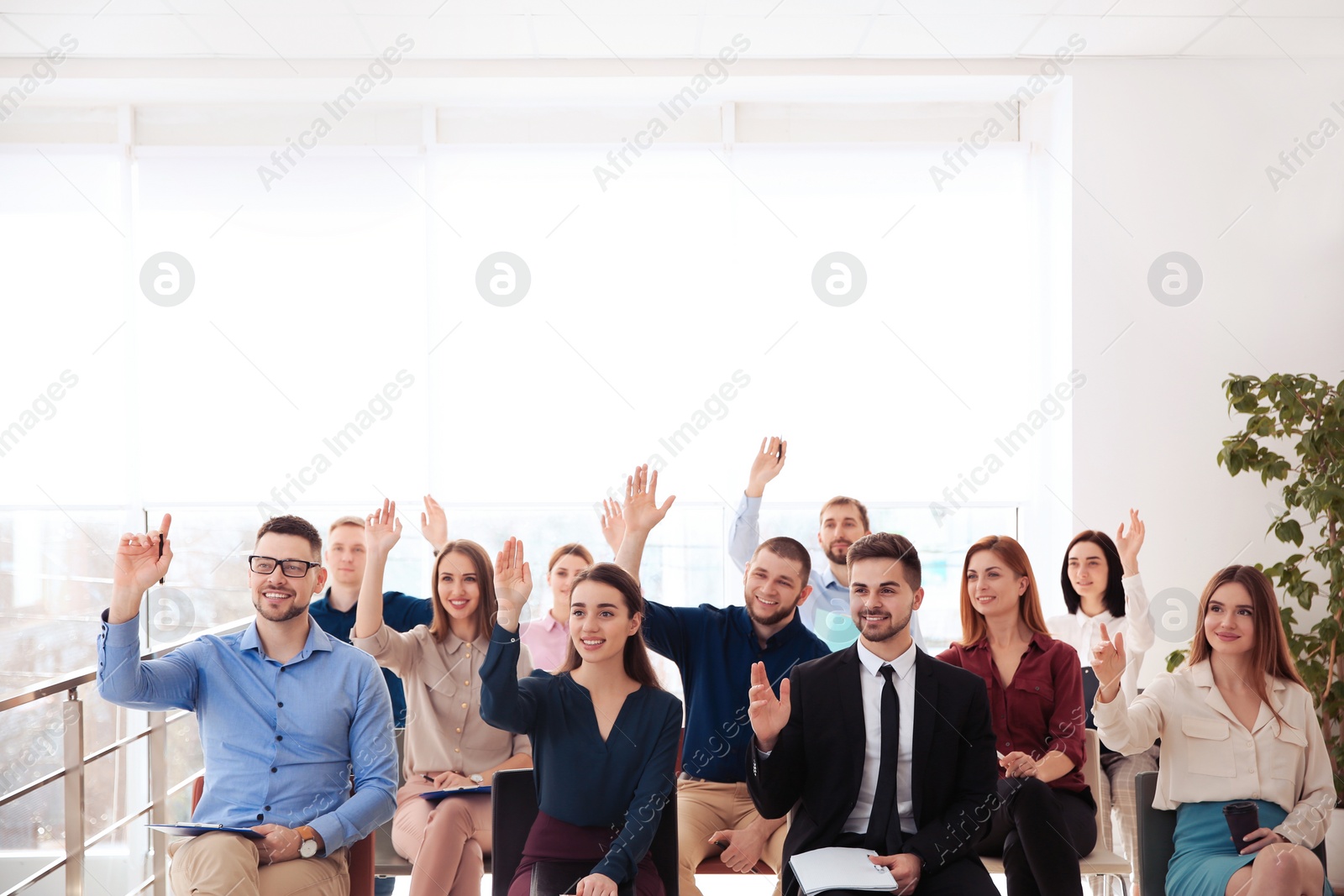 Photo of People raising hands to ask questions at business training indoors