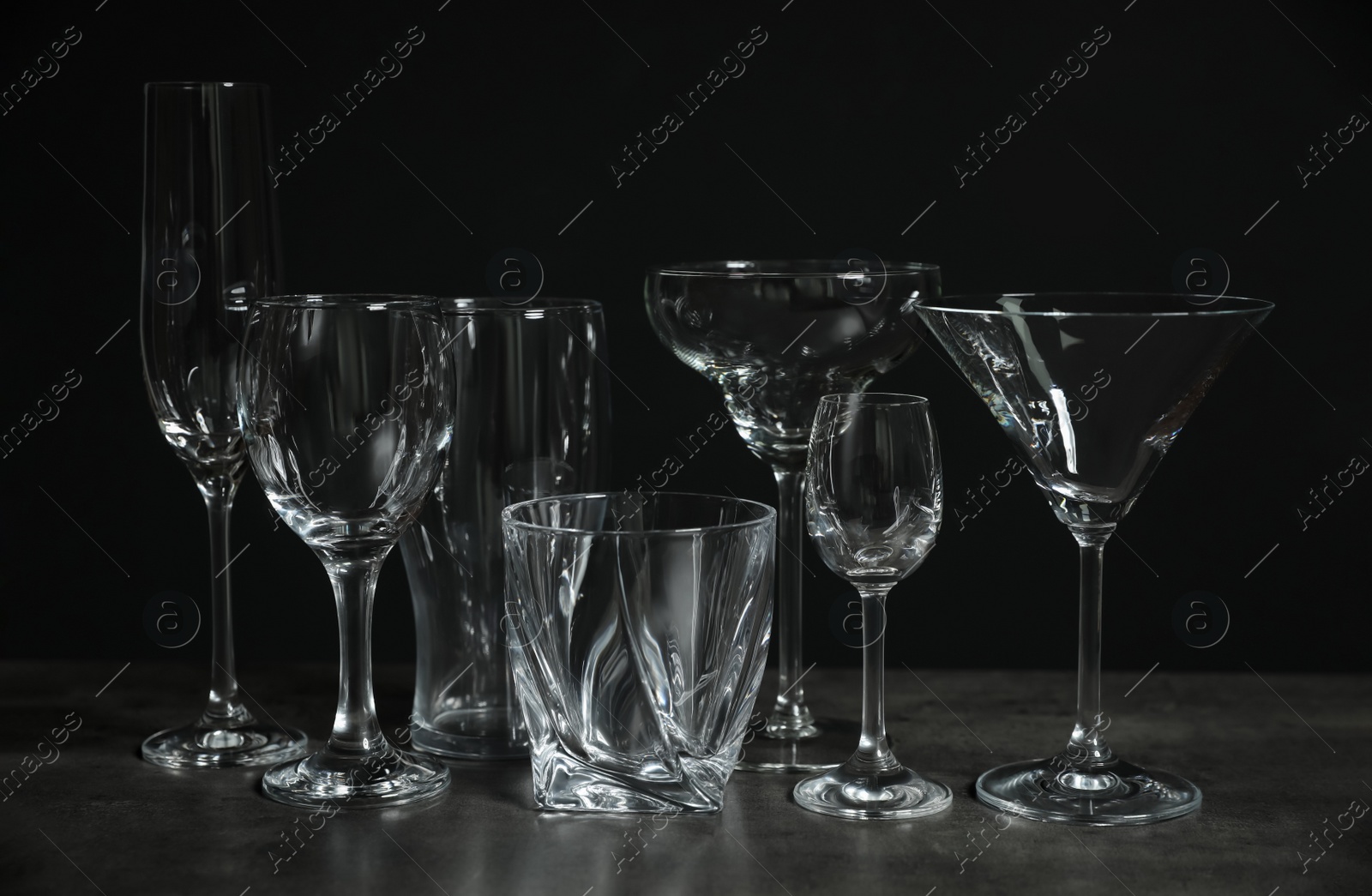 Photo of Set of bar glassware on table against dark background