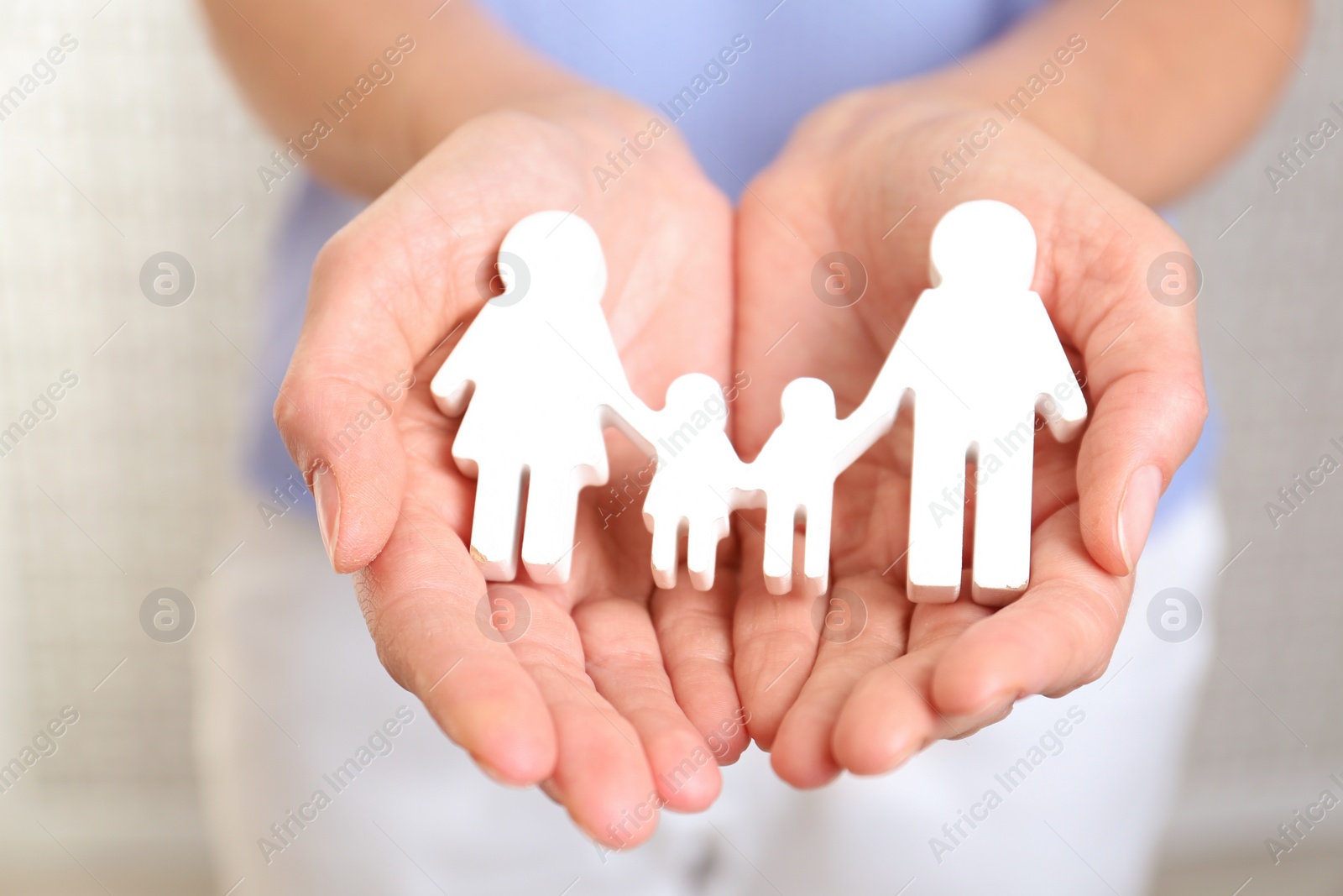 Photo of Young woman holding wooden family figure, closeup of hands