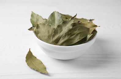Photo of Dry bay leaves in bowl on white wooden table