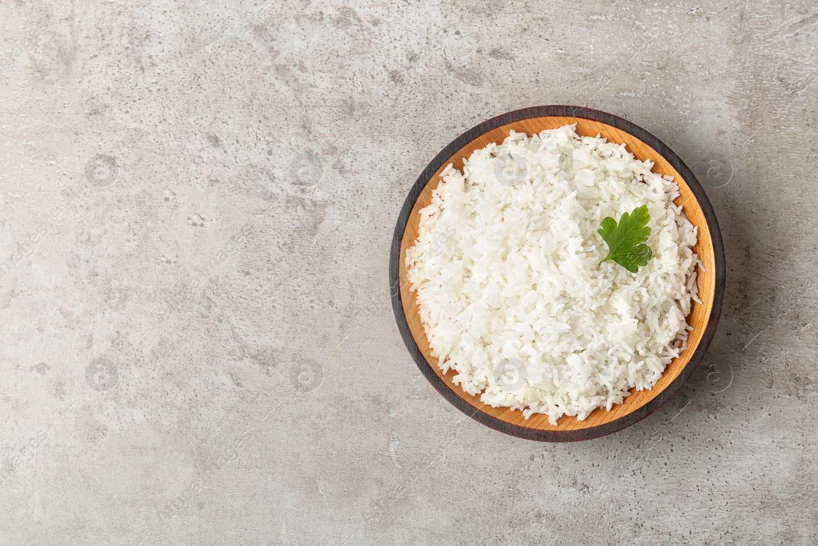 Photo of Bowl of boiled rice on grey background, top view with space for text