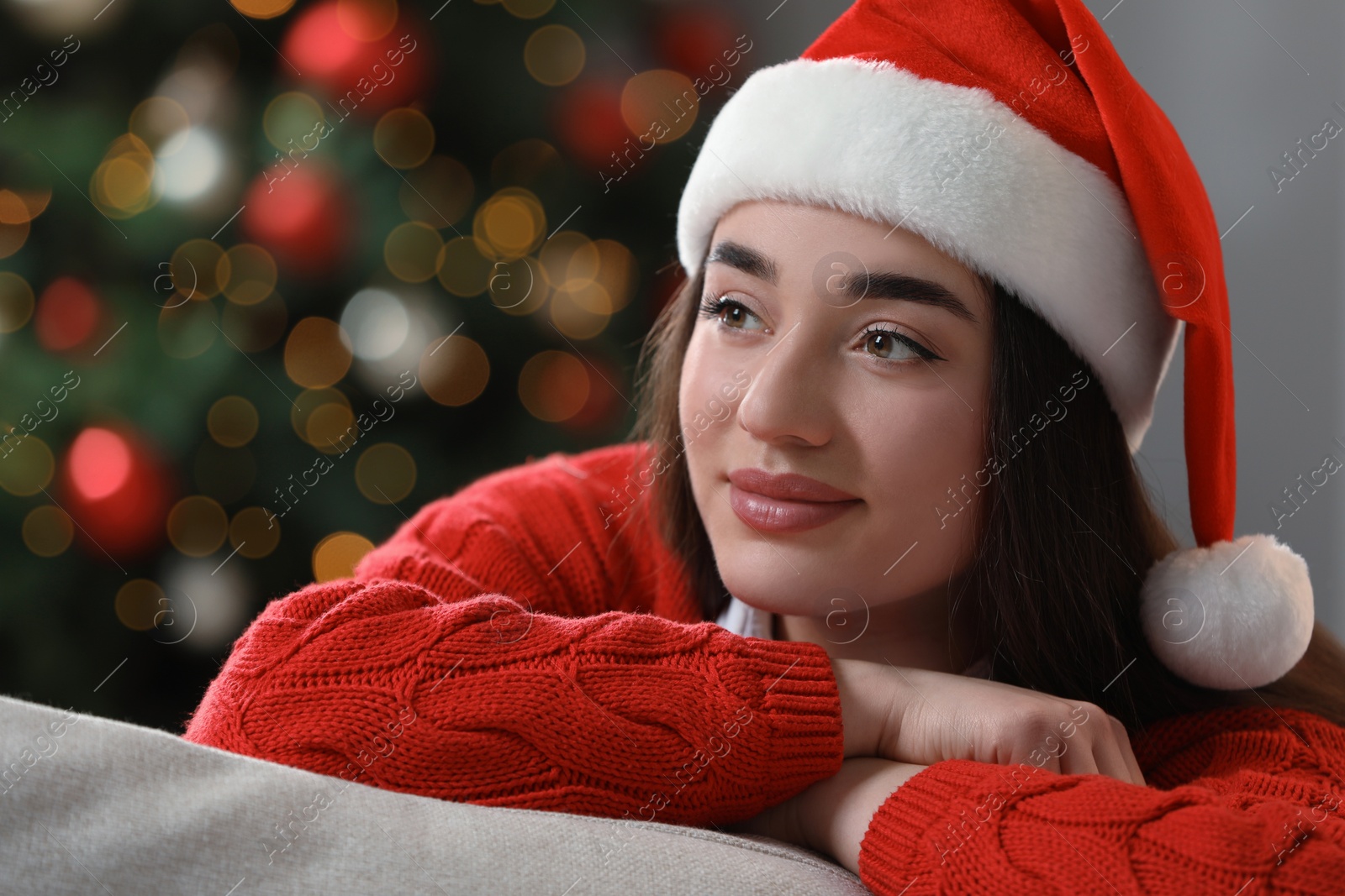 Photo of Beautiful woman wearing red Christmas hat against blurred lights