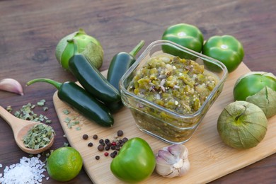 Photo of Tasty salsa sauce and ingredients on wooden table