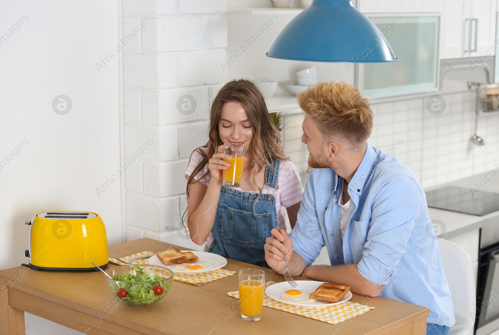 Photo of Happy young couple having breakfast at table in kitchen