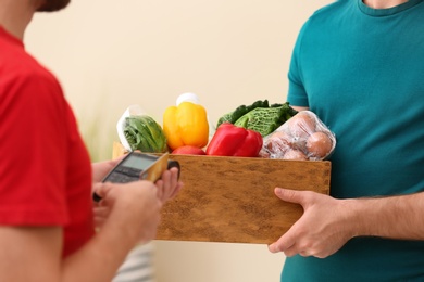 Photo of Customer using credit card terminal to pay for food delivery indoors, closeup