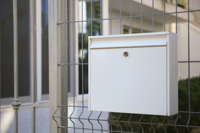 Photo of White metal letter box on fence outdoors