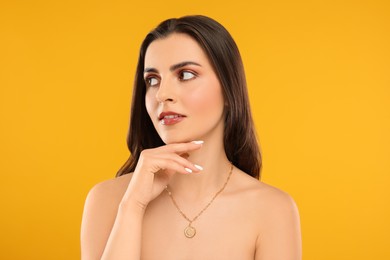 Beautiful woman with elegant necklace on orange background