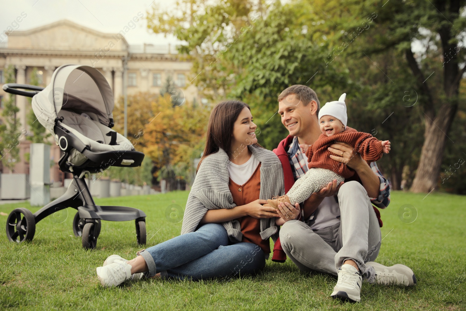 Photo of Happy parents with their adorable baby on green grass in park