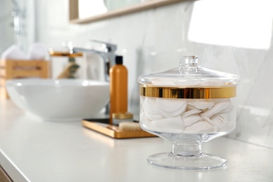 Photo of Jar with cotton pads on bathroom countertop