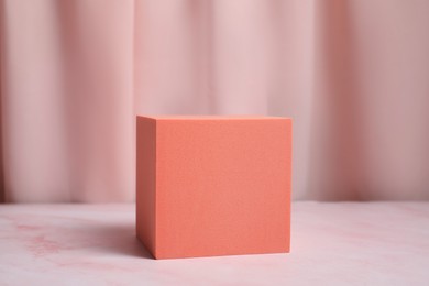 Photo of Orange geometric figure on pink marble table. Stylish presentation for product