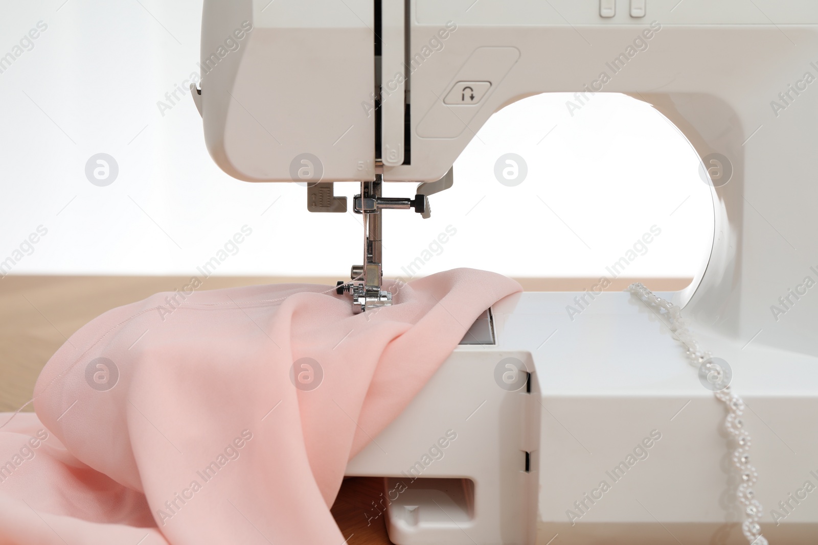 Photo of Sewing machine with fabric on table against white background, closeup