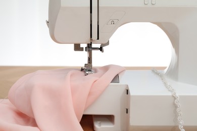 Sewing machine with fabric on table against white background, closeup