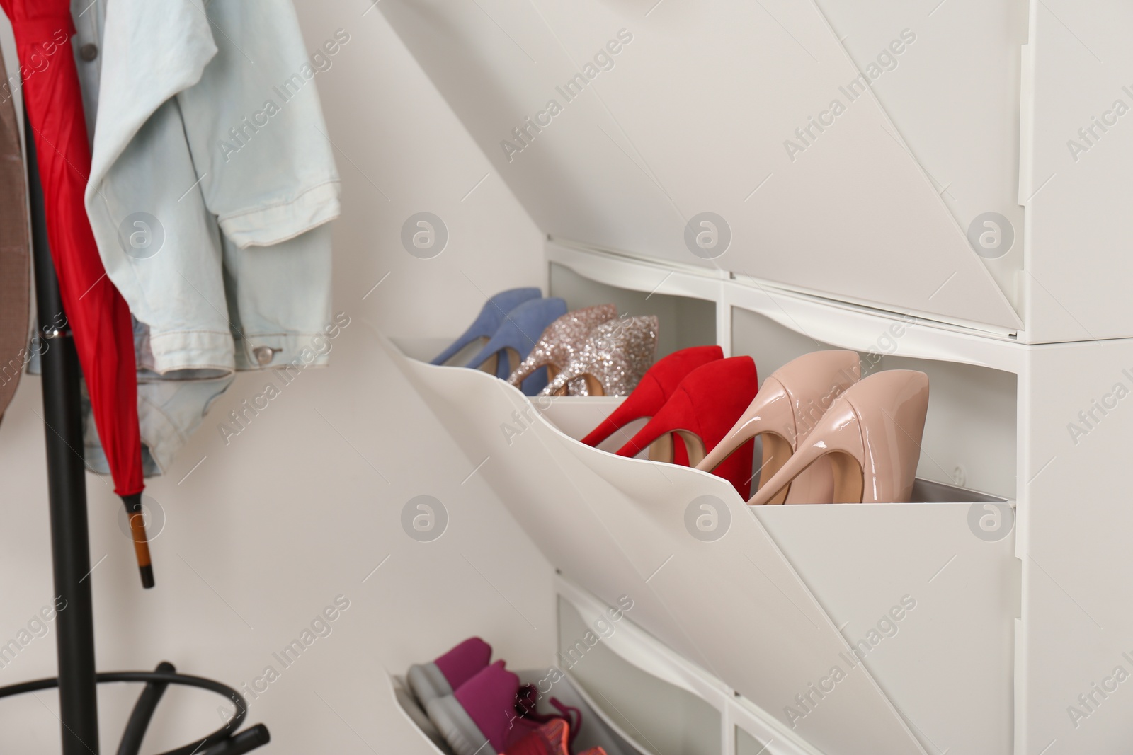 Photo of Shoe cabinet with footwear in room. Storage ideas